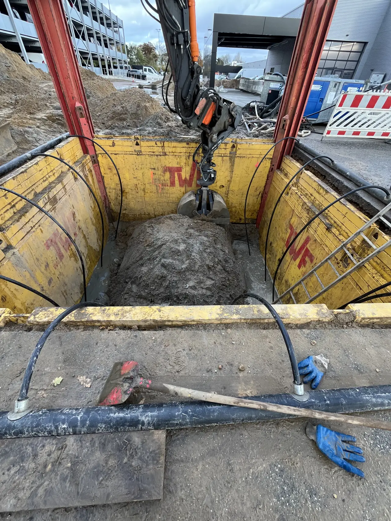 Bagger bei Aushubarbeiten in einer gesicherten Baugrube.