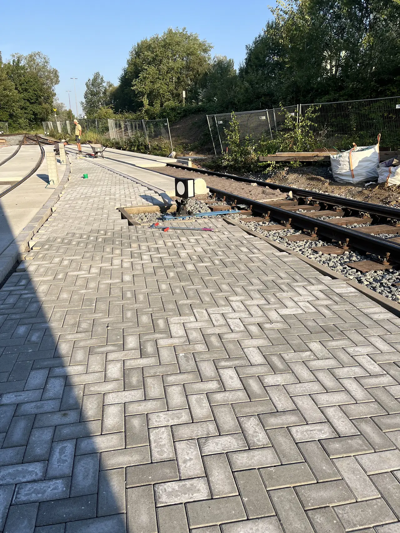 Gepflasterte Fläche neben Gleisen.