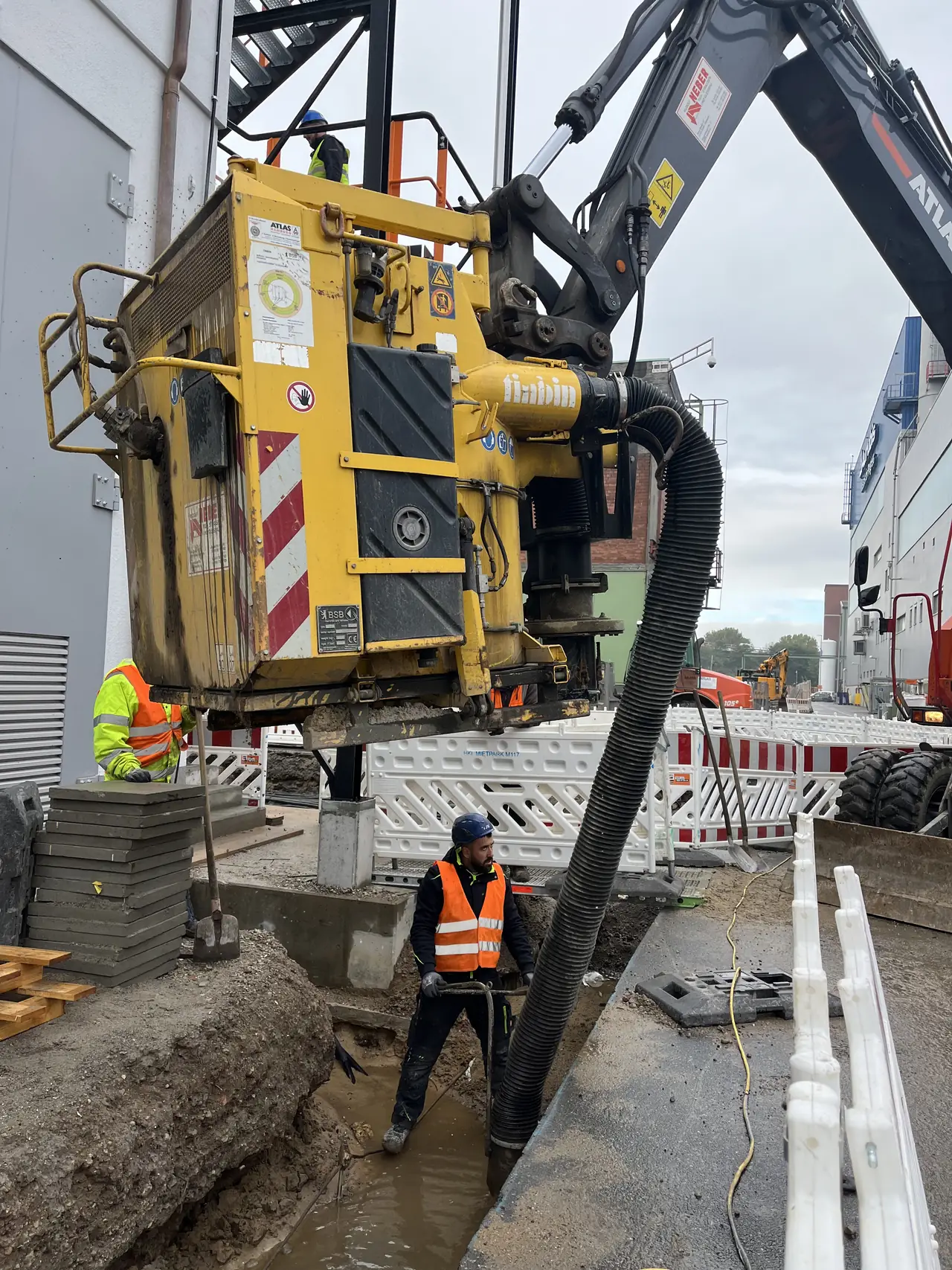 Mitarbeiter bei Bauarbeiten mit einem Bagger und Anbaugerät.